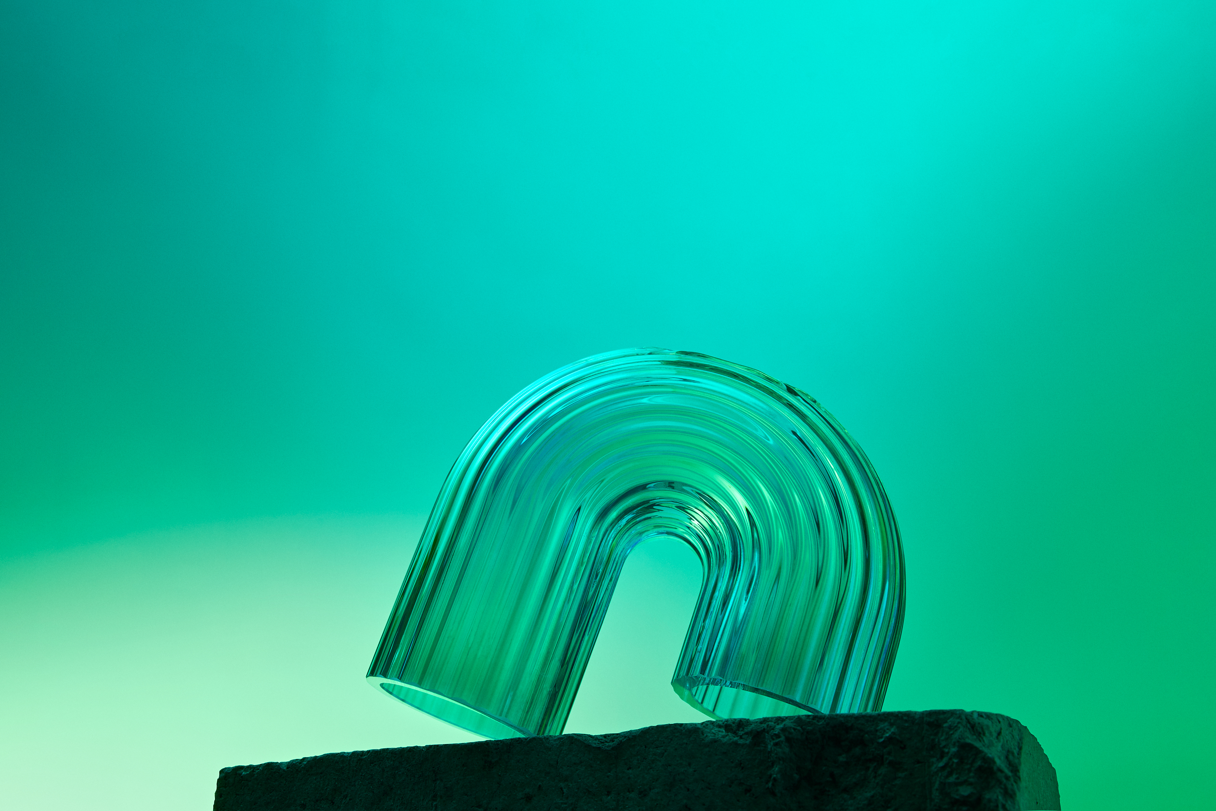 Hourglass with black sand on a concrete plinth against teal background